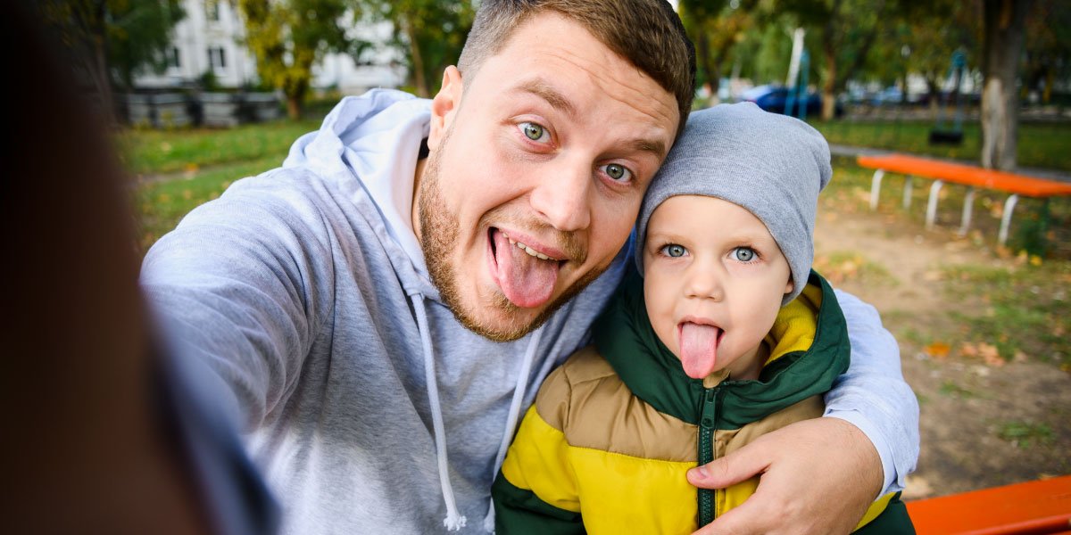 Vater und Sohn machen ein Selfie mit herausstehender Zunge