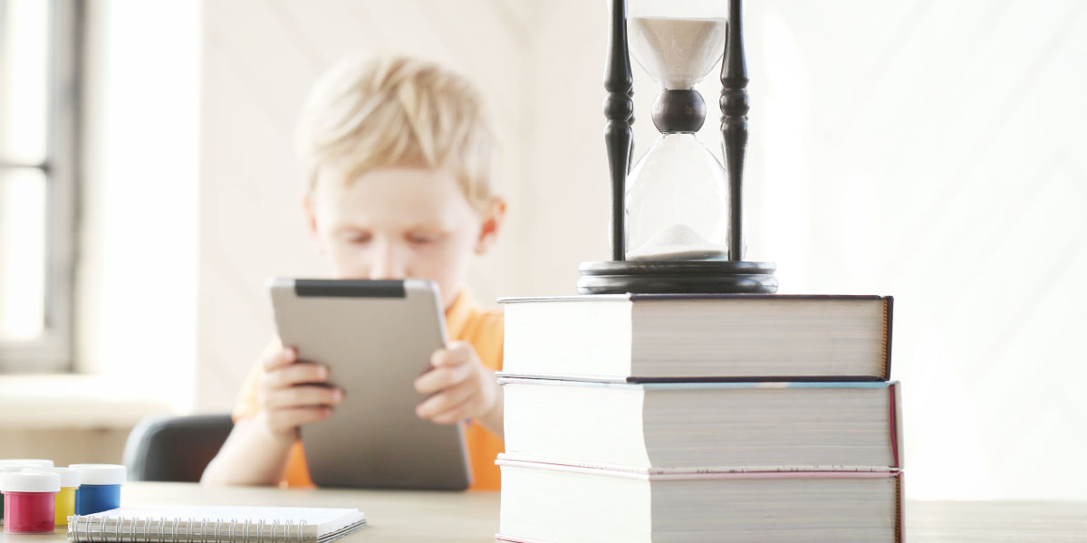 Boy looking at tablet with books around