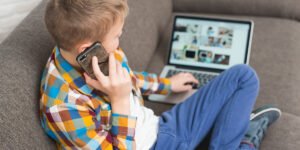 a Kid Browsing on a Computer while talking on the phone