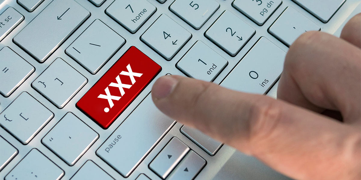 A person tapping a key on a keyboard that reads .XXX