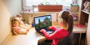 little girl playing minecraft on her laptop