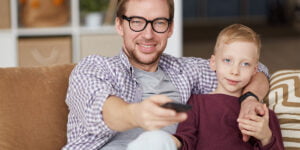 Father setting parental controls on Fire TV or Firestick with child sitting next to him