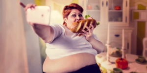 Obese woman eating a sandwich while taking a selfie