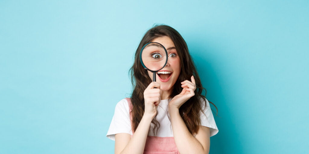 a lady is smiling and using her magnifying glass to look for ways to provide a safe image search for kids