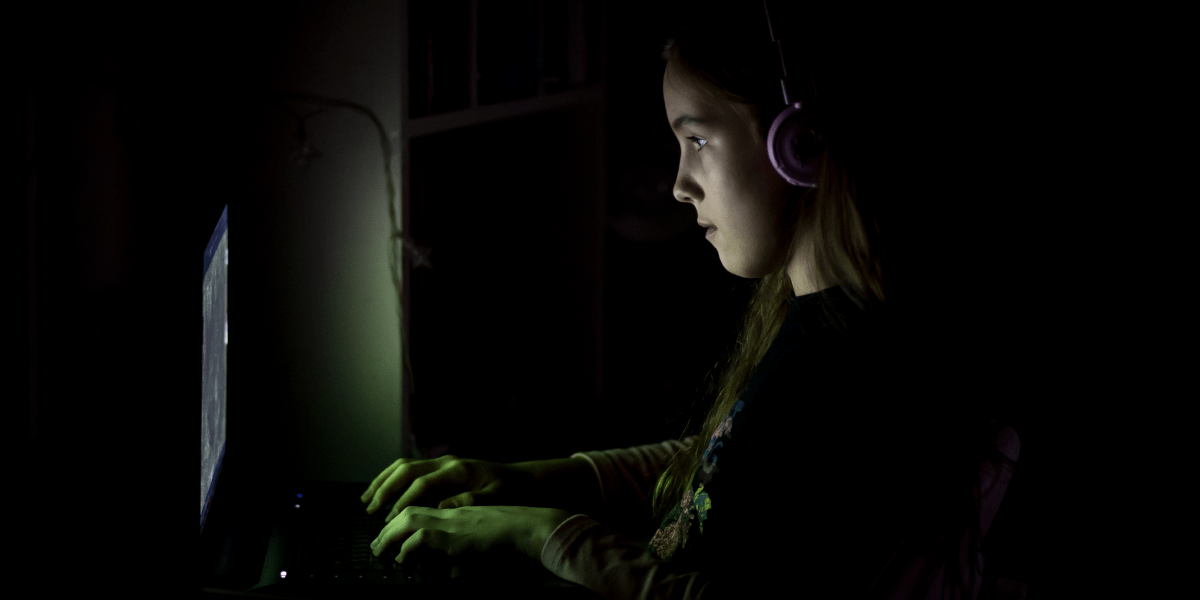 A little girl in the dark, staying up late using her computer