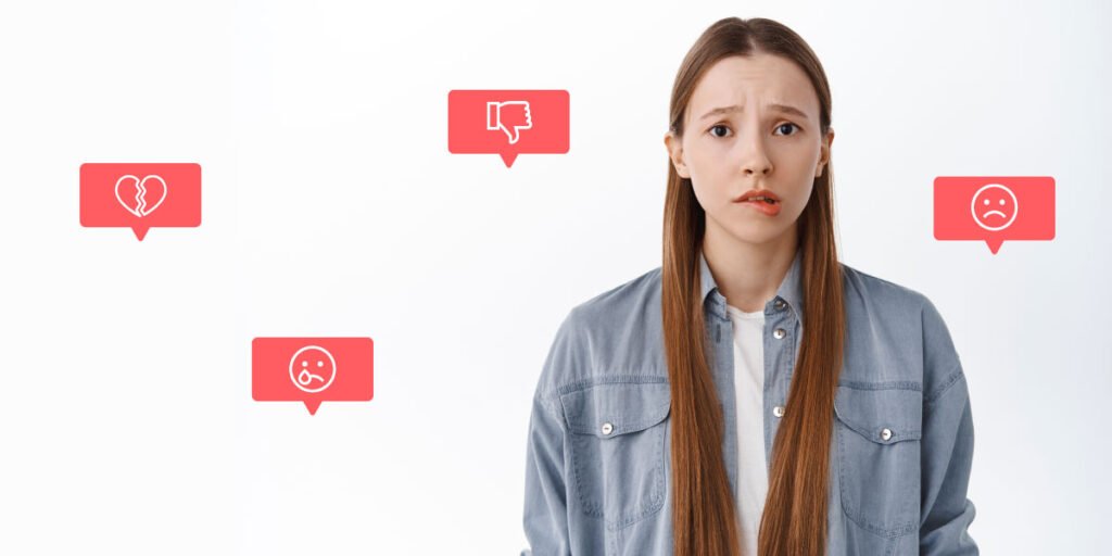 Ein trauriges und nervöses Teenager-Mädchen, das sich auf die Lippe beißt, umgeben von Social-Media-Abneigungen und traurigen Emojis, die ihr Selbstwertgefühl senken
