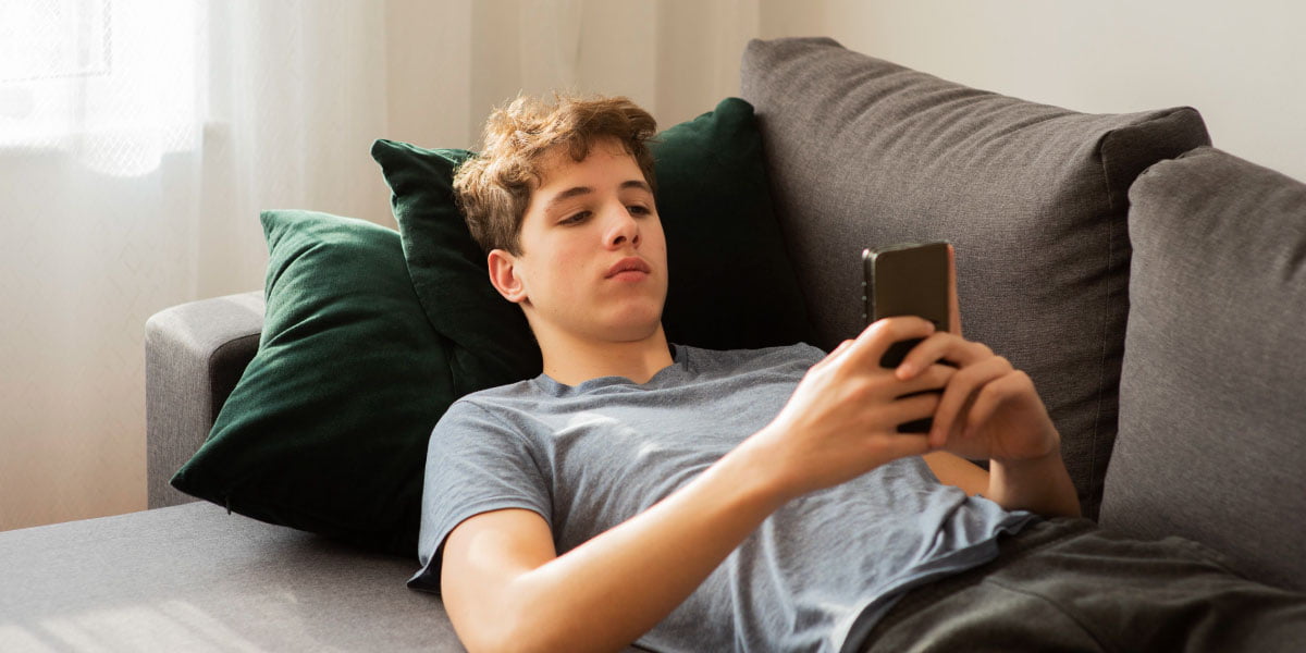 Teenage boy lying on a couch using his phone