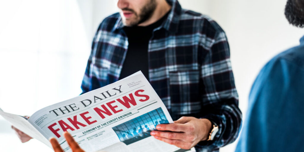 Man holding a newspaper that reads “The Daily: Fake News”