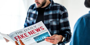 Man holding a newspaper that reads “The Daily: Fake News”