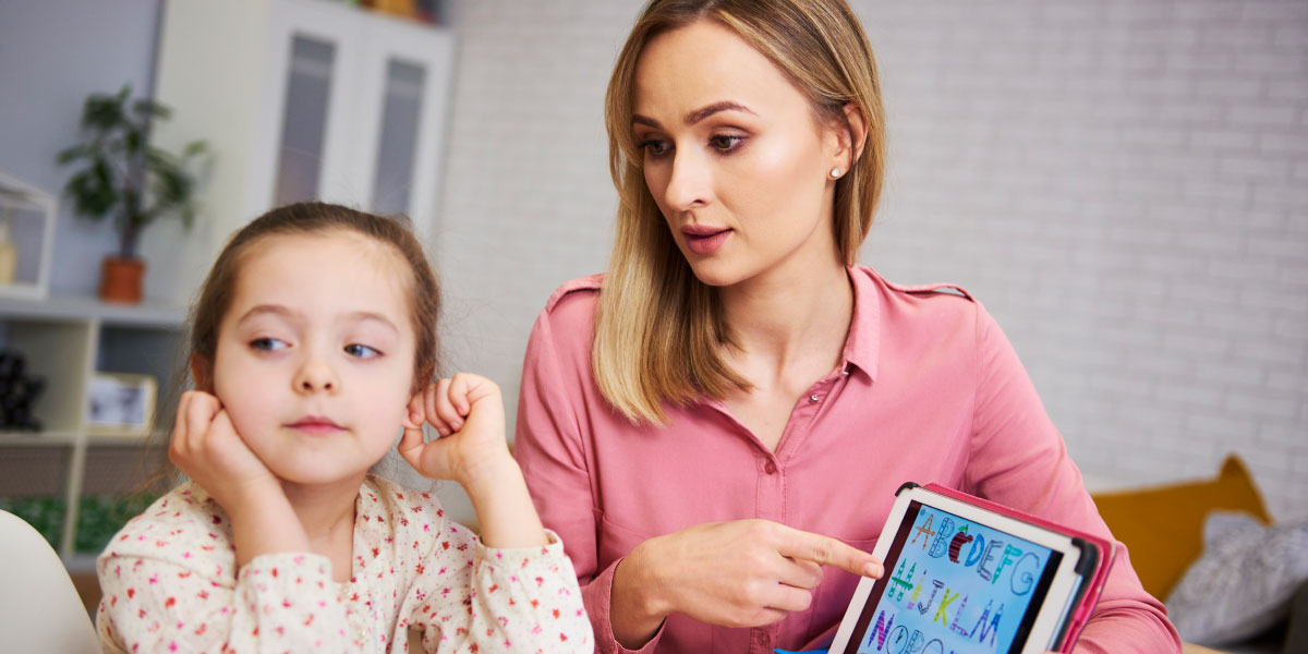 Gelangweiltes Mädchen und ihre Mutter lernen mit Laptop zu Hause