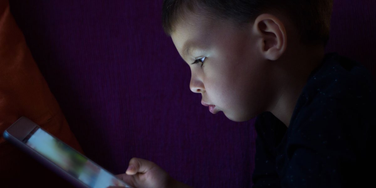 A child is using a tablet in the dark