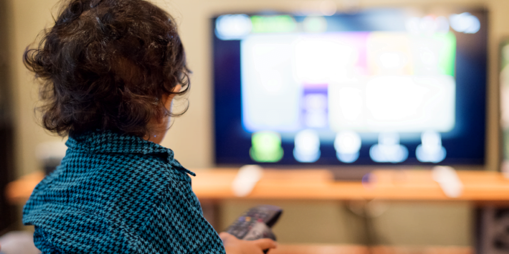 Toddler with remote in hand watching television