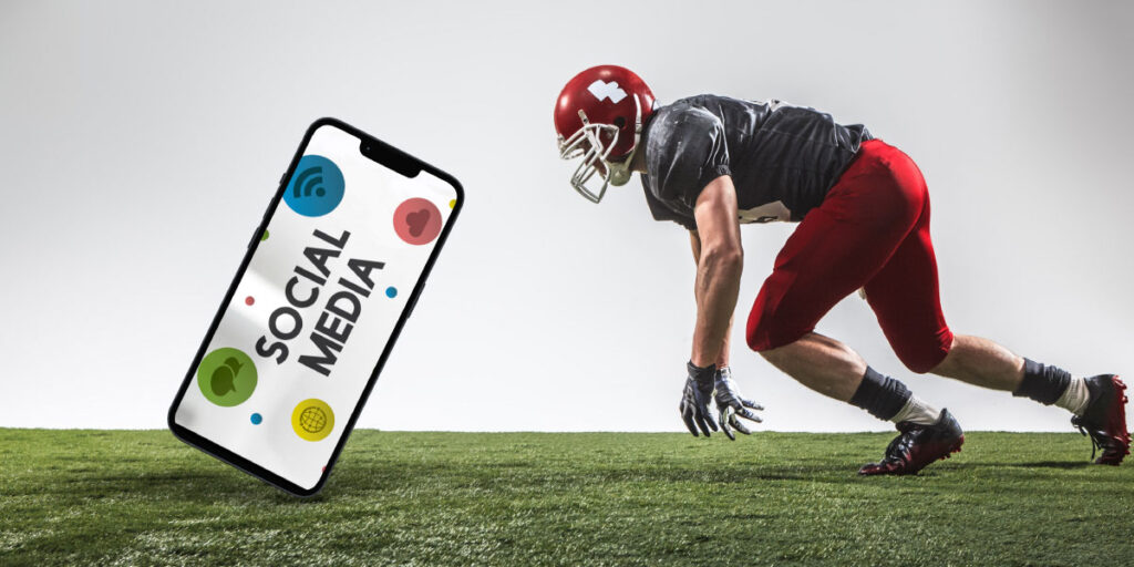 An American football player on a field, diving to catch an unusually big smartphone with social media on the screen
