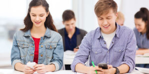 Two students using their phone in a classroom