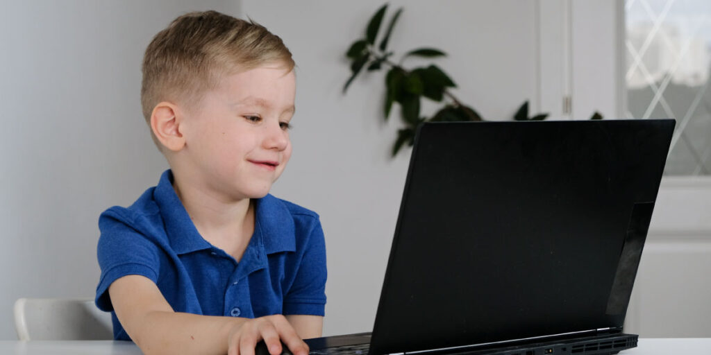 hild sitting behind a desk and pointing at a computer screen.