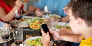 Child using phone at family dinner