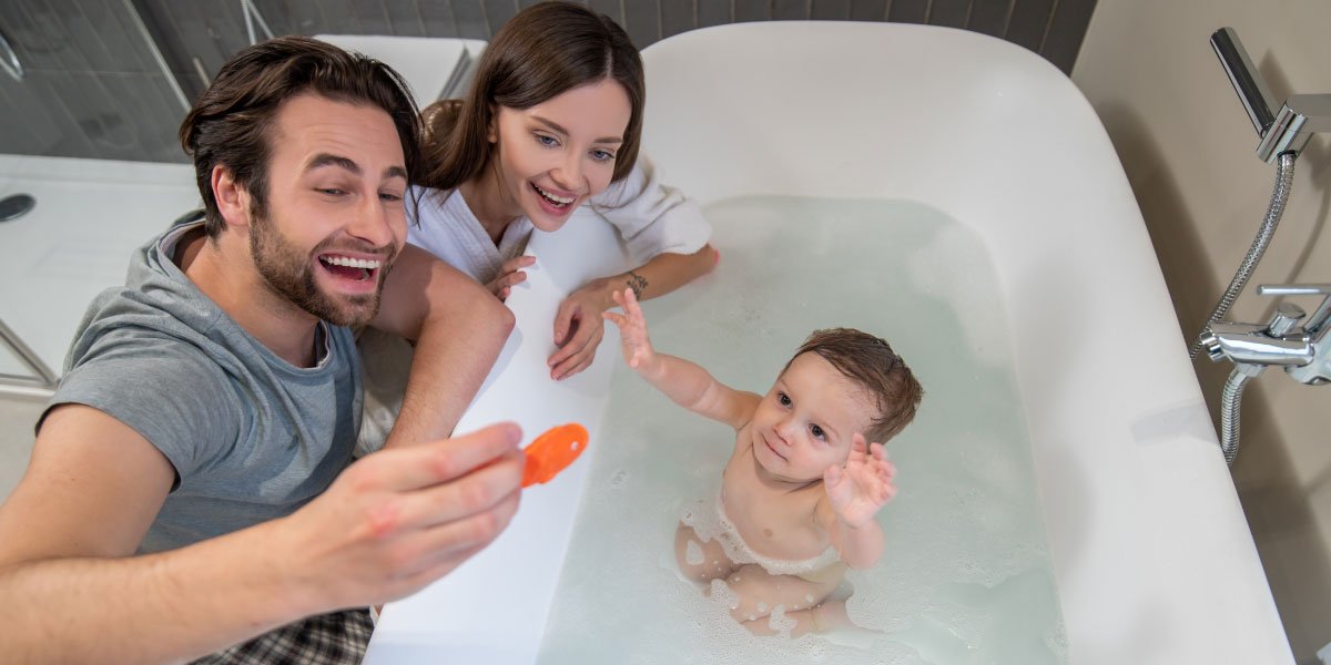 Parents playing with their child in a bathtub