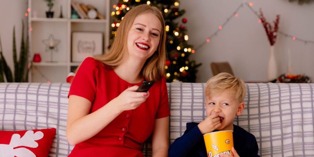 Mother sitting with her child with a bucket of popcorn watching tv