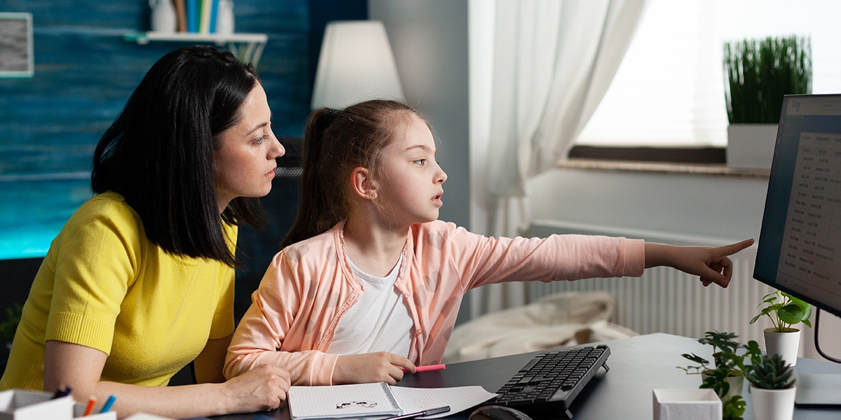 School kid showing her mother something on a monitor