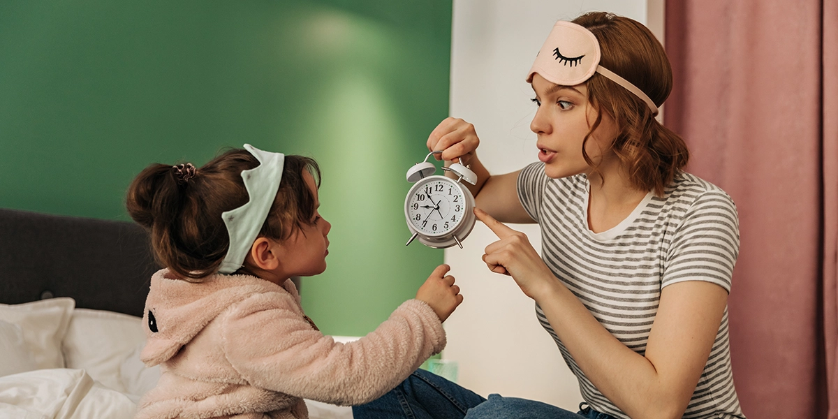 Mother showing an alarm clock to a toddler