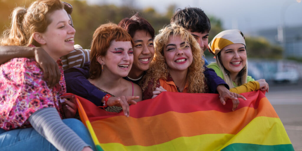 Teenagers from different cultures holding the LGBTQ flag