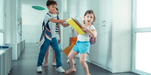 Rude violent boy pushing little darkhaired girl