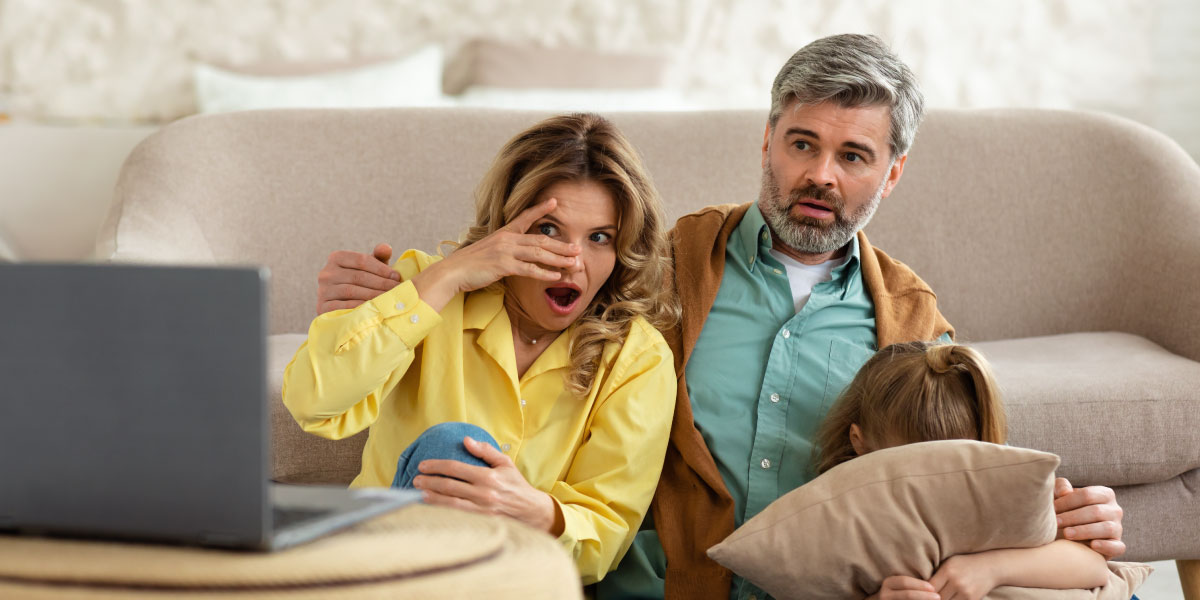 Shocked parents and little daughter looking at laptop at home
