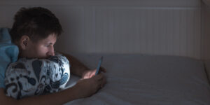 Teen boy using a smartphone in bed
