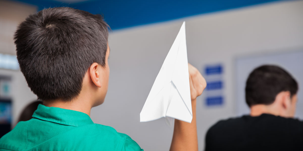 ungezogener Gymnasiast, der während des Unterrichts ein Papierflugzeug wirft