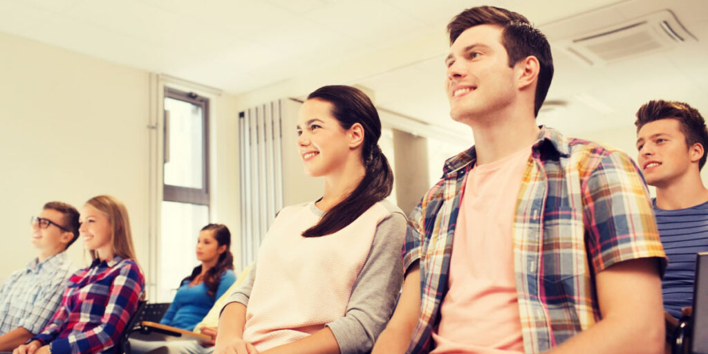 group of smiling students sitting in lecture hall