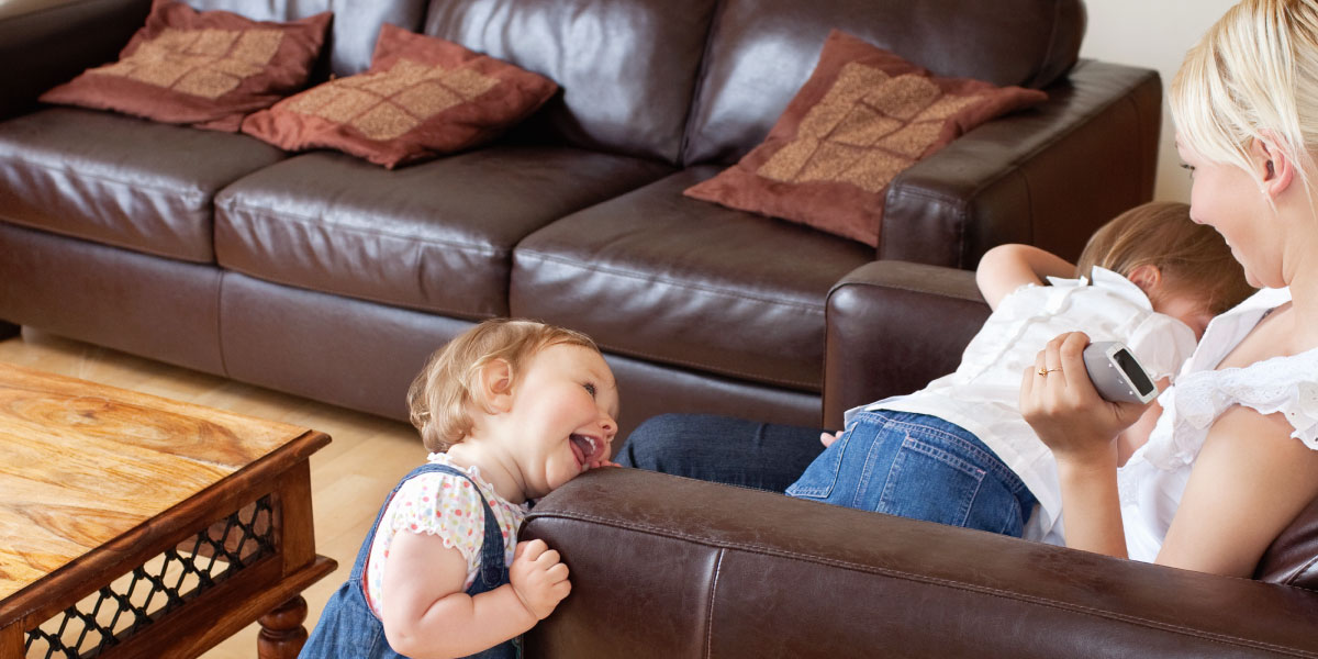 Laughing mother watching TV with two children