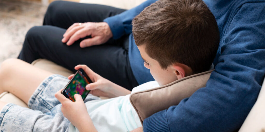 child sitting next to parent with phone in his hands