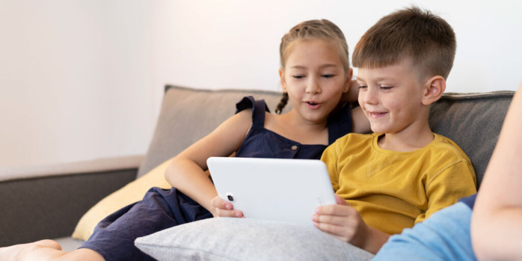 Two girls sitting next to each other and using their iPad