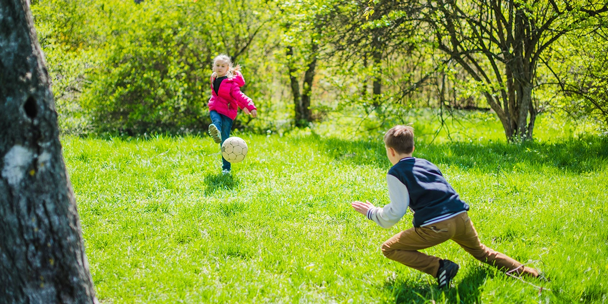 Boy and girl playing with a ball in nature