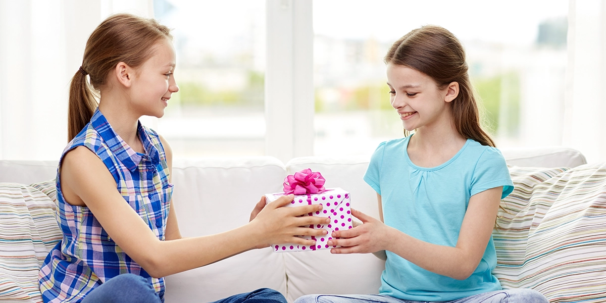 Young girl giving a gift to another girl