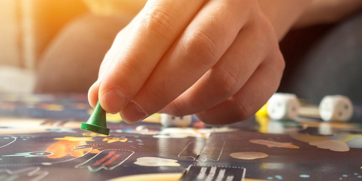 Hand of a child moving figures on a budgeting board game