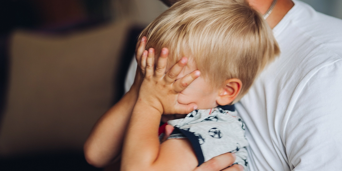 stressed little boy with his hands over his face