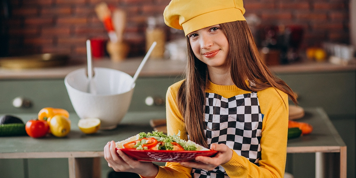 School girl cook holding a plate with food