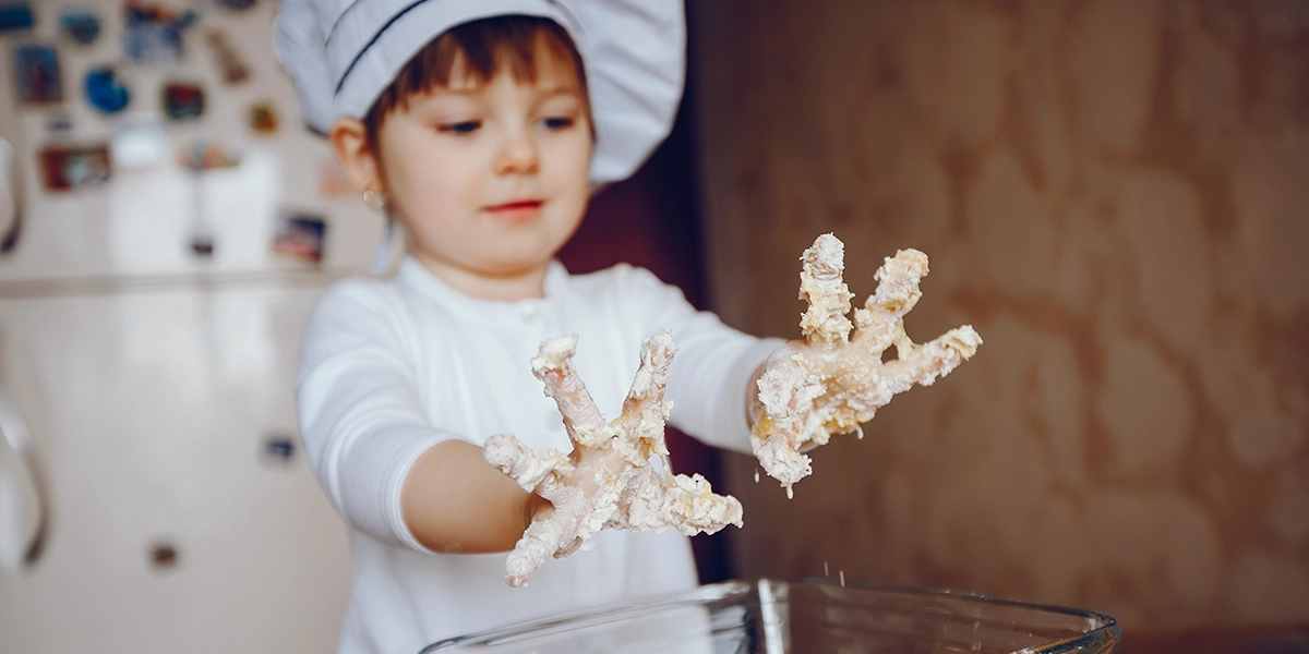 Little girl chef with her hands in dough