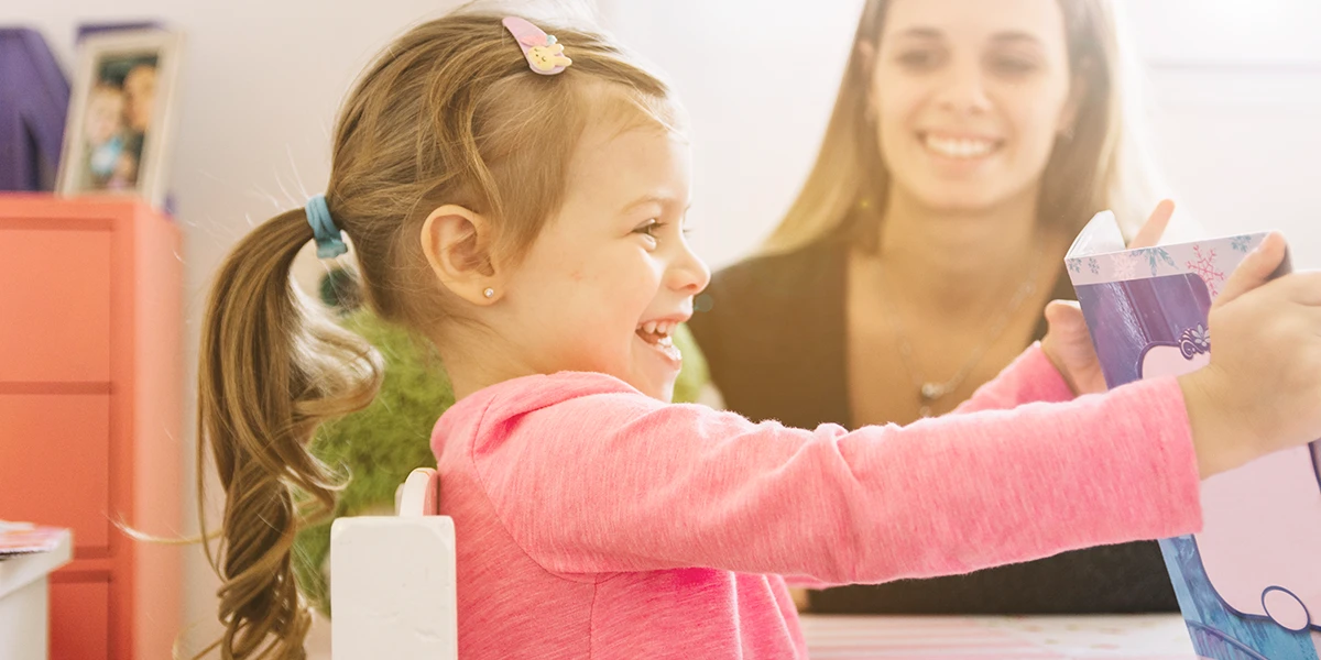 girl sitting next to her mother and playing with toy