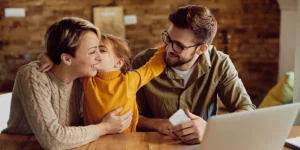 Happy daughter embracing and kissing her parents at home