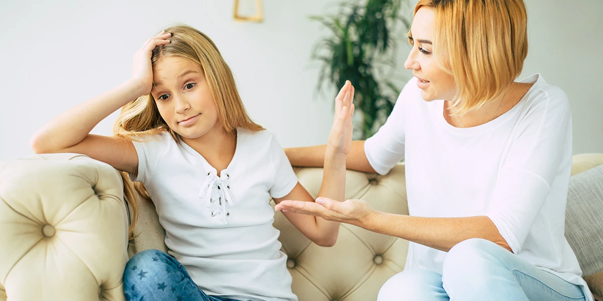 Girl holding her palm out to her mother pretending not listening to her