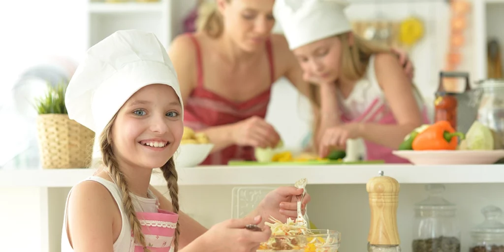 zwei Mädchen kochen mit ihrer Mutter