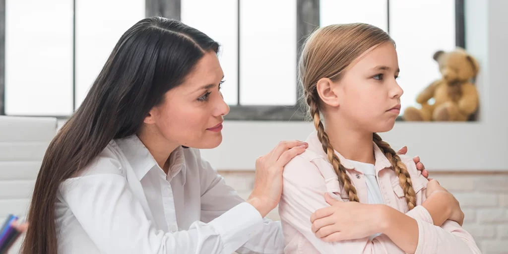 Mother trying to approach a girl who has turned her back, looking as if she is not willing to listen