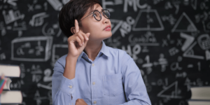 Teenager looking as if he is thinking critically about something on background of a blackboard covered in scientific scribble