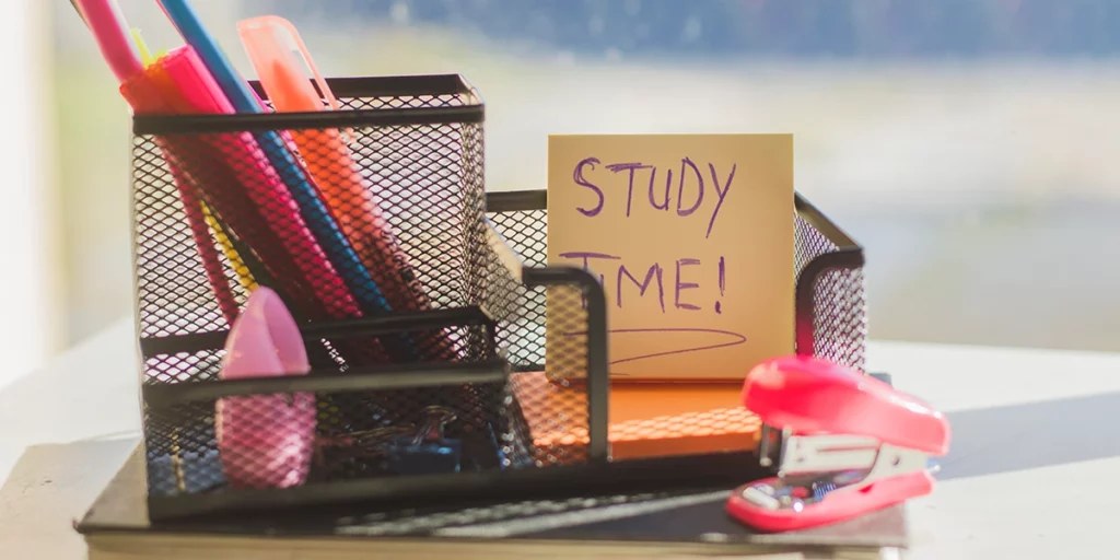 Close-up of stationeries on a desk with a note that reads “Study Time!”