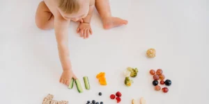 baby picking up cucumbers from a range of different fruits and vegetables