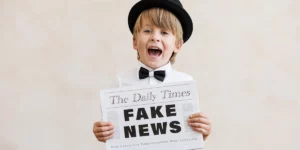 boy holding a fake Daily Times newspaper with FAKE NEWS written on it