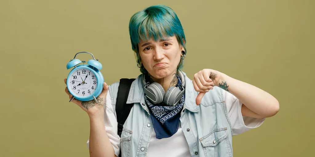 Teenage girl holding an alarm clock looking sad as if she is unable to manage time