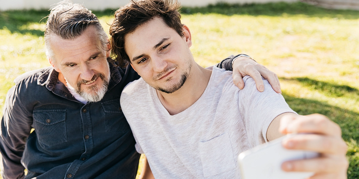Father and teenage son taking a selfie